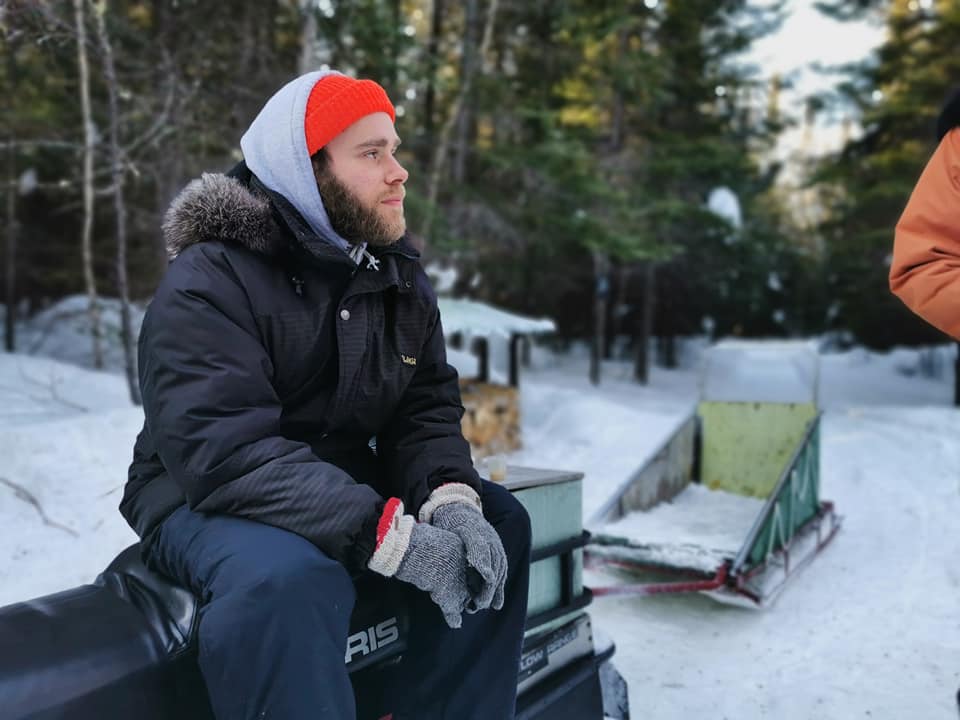 Adam Faucher, le directeur artistique de l'Agora des arts de Rouyn-Noranda, en Abitibi-Témiscamingue, profite de la nature assis sur une motoneige. 